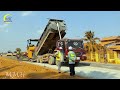 Awesome of a line of gravel dump trucks on the road & a massive gravel yellow paver machine working