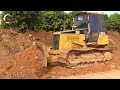 The bulldozers push a large pile of dirt. A new road construction site with two yellow bulldozers