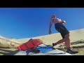 Paddleboard dog runs down some sand dunes with his human