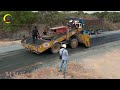 A road construction with a gravel spreading truck and dump trucks work together to lay down gravel.